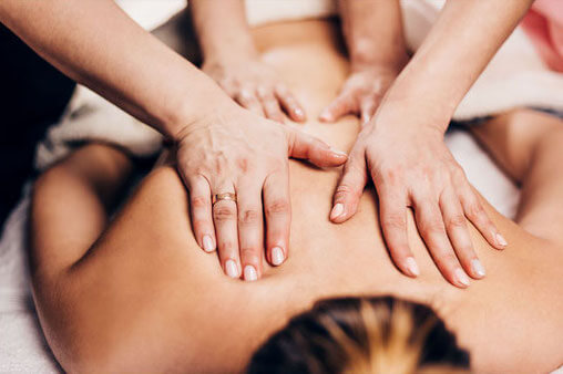 Dos d'une femme se faisant masser à 4 mains.