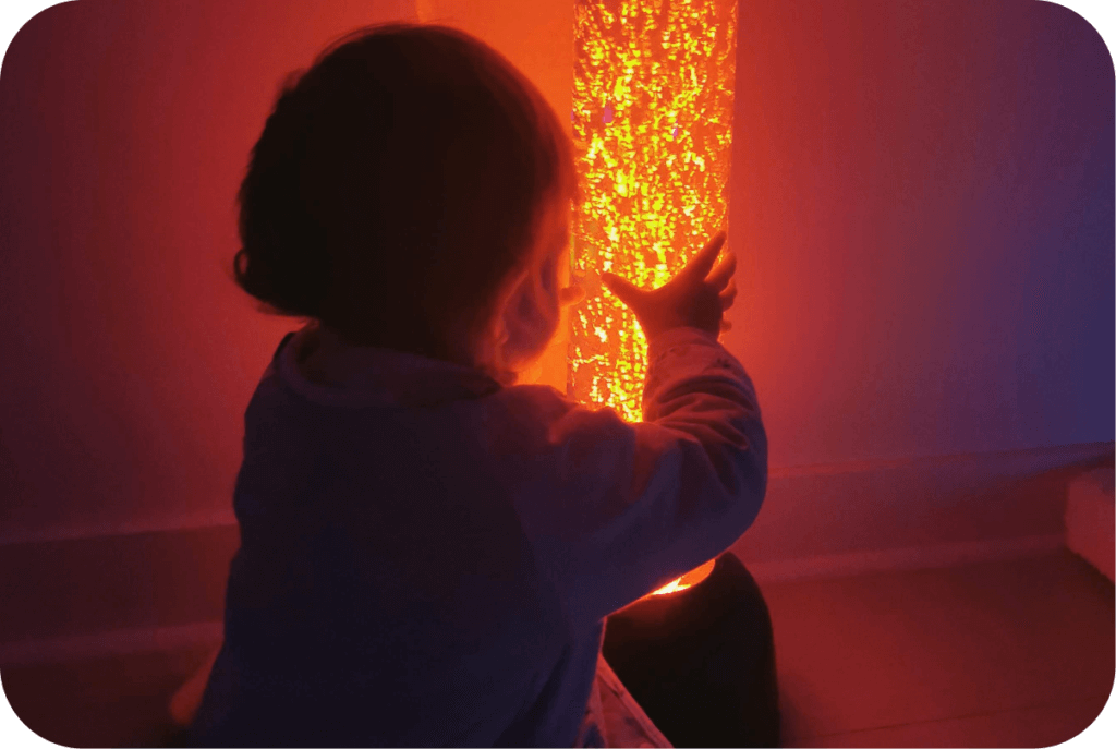 Enfant qui pose ses mains sur une colonne lumineuse orange
